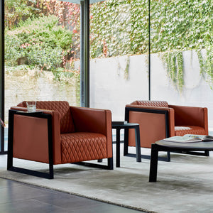 two beautiful diamond quilted sofa armchairs sit side by side across from Australian designer sofas in a velvety grey rug